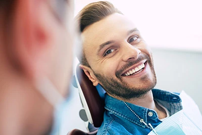 man smiling in the dental chair while visiting Hrencher Dental